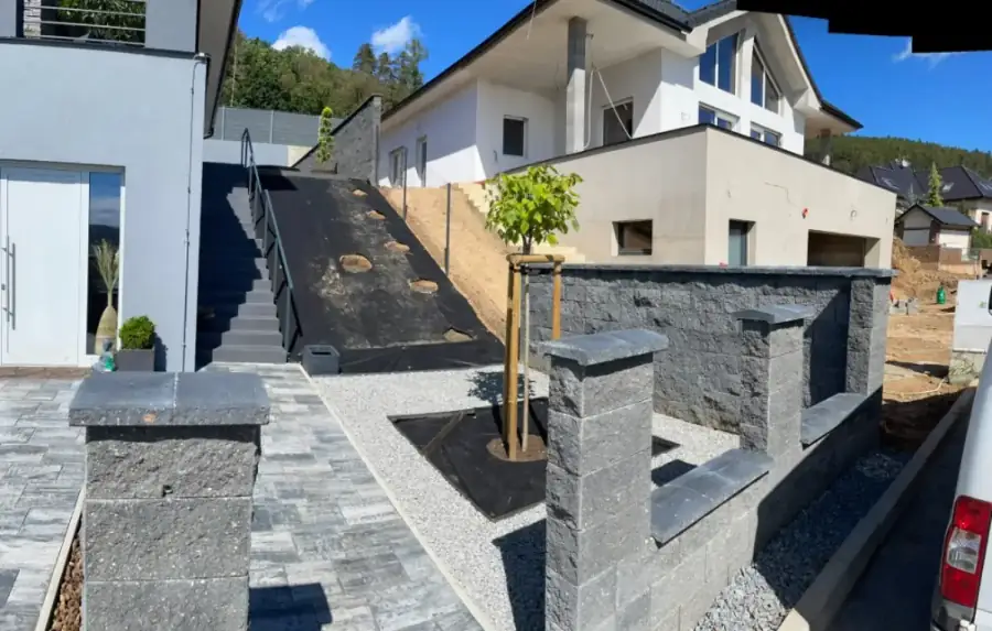 Terénní úpravy, dlažba a opěrná zeď u novostavby, výsadba stromků